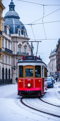 A red tram travels through snowy streets