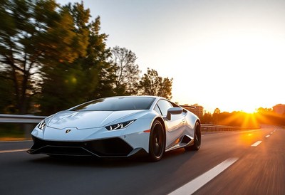 A white sports car drives down a road at sunset