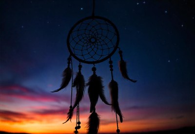 A dreamcatcher hangs in the sky at sunset