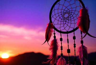 A dreamcatcher hangs against a purple sunset