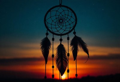 A dreamcatcher hangs against the sunset