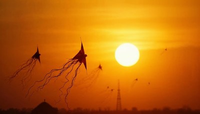 Colorful kites flying at sunset over a serene landscape