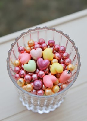 Colorful candy hearts and pearls in a glass container