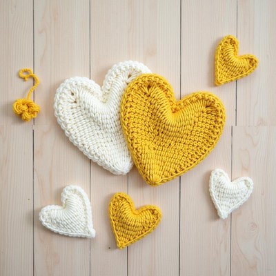 Handmade knitted hearts in various sizes on wood surface