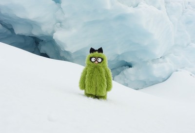 Green furry creature stands in snowy landscape near glacier