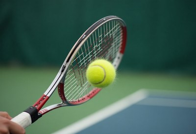 Tennis player hits a yellow ball with a racket