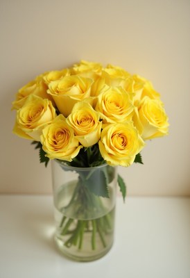 Bright yellow roses arranged in a clear vase on a table