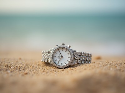 Elegant watch rests on sandy beach during sunny day