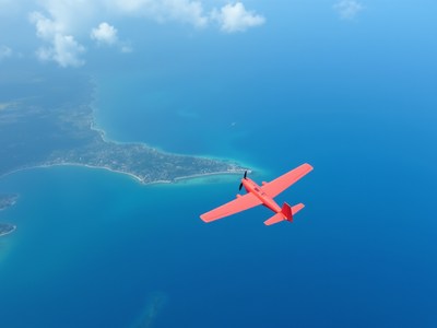 Colorful aircraft flying over coastal landscape and ocean