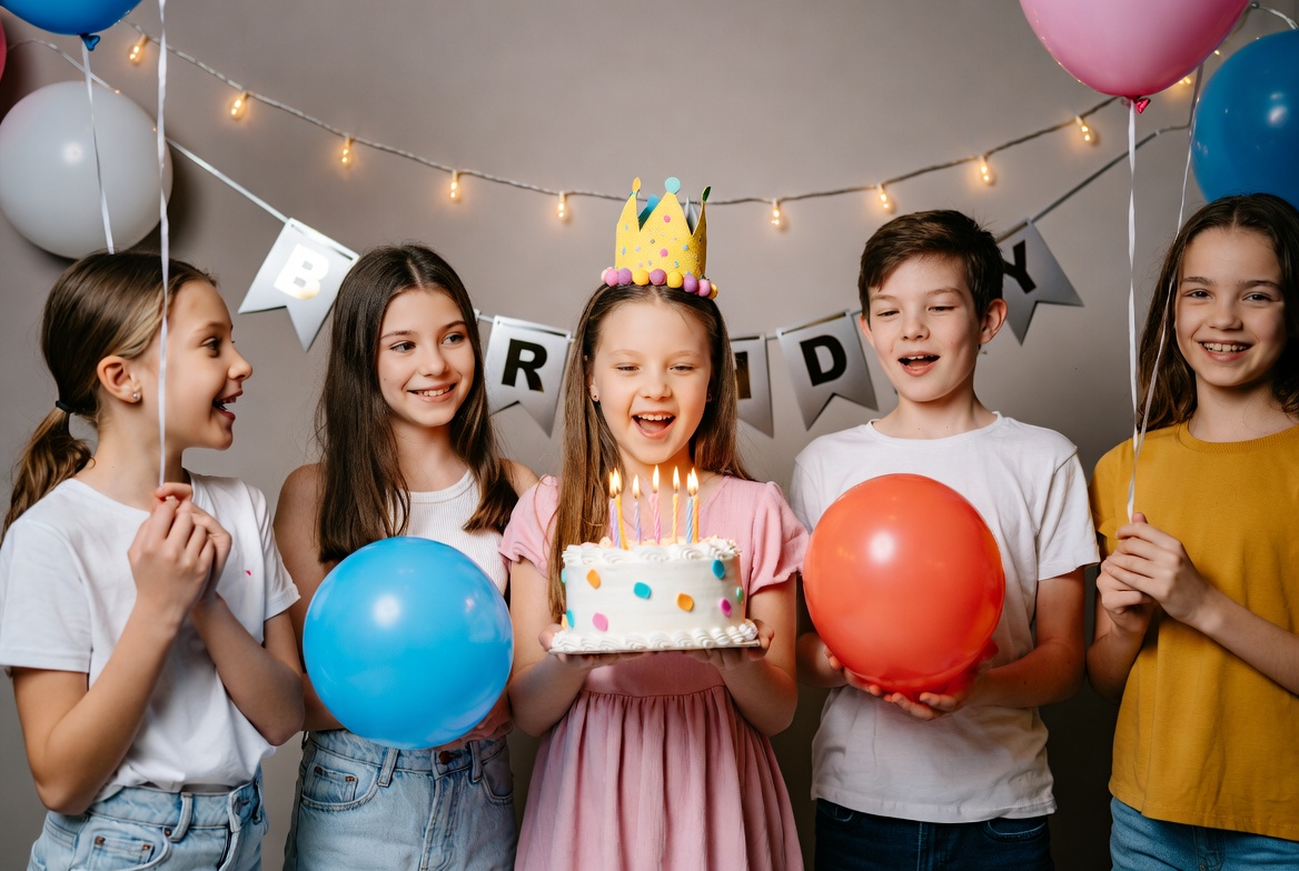 Children celebrating a birthday with a cake and balloons Children celebrating a birthday with a cake and balloons