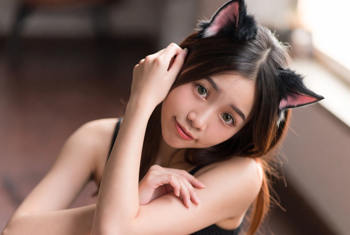 Young woman with cat ears posing indoors in soft light Young woman with cat ears posing indoors in soft light