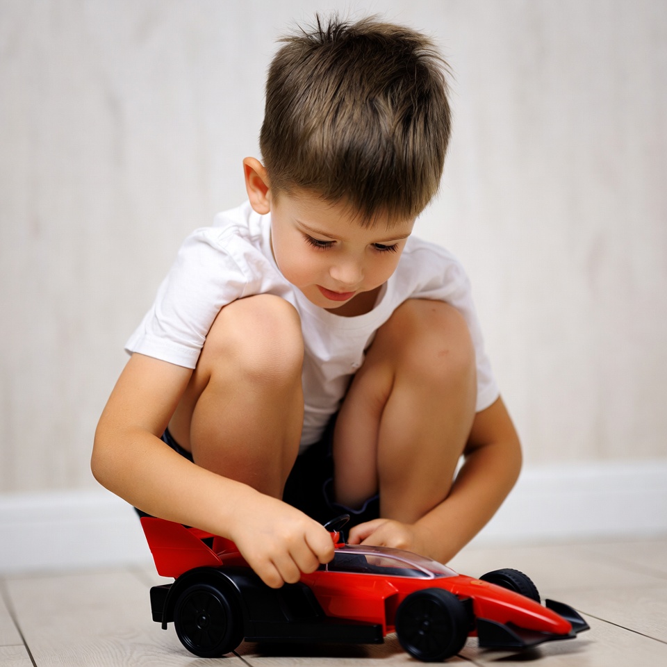 Boy playing with red toy car Boy playing with red toy car