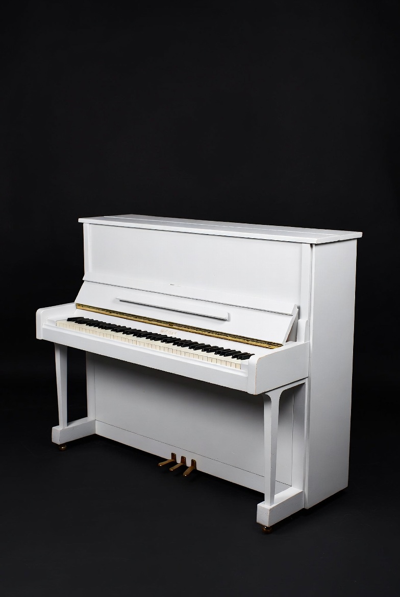 Elegant white upright piano against dark backdrop Elegant white upright piano against dark backdrop
