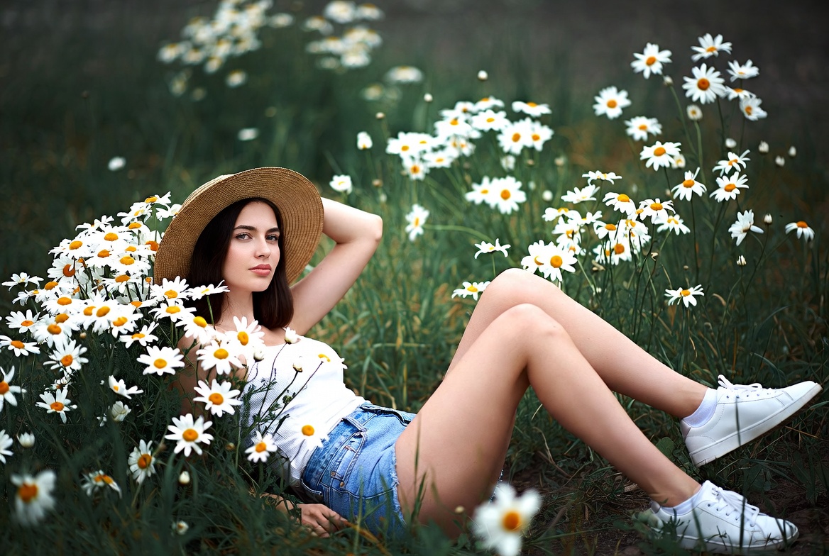 Model lying among daisies in field Model lying among daisies in field