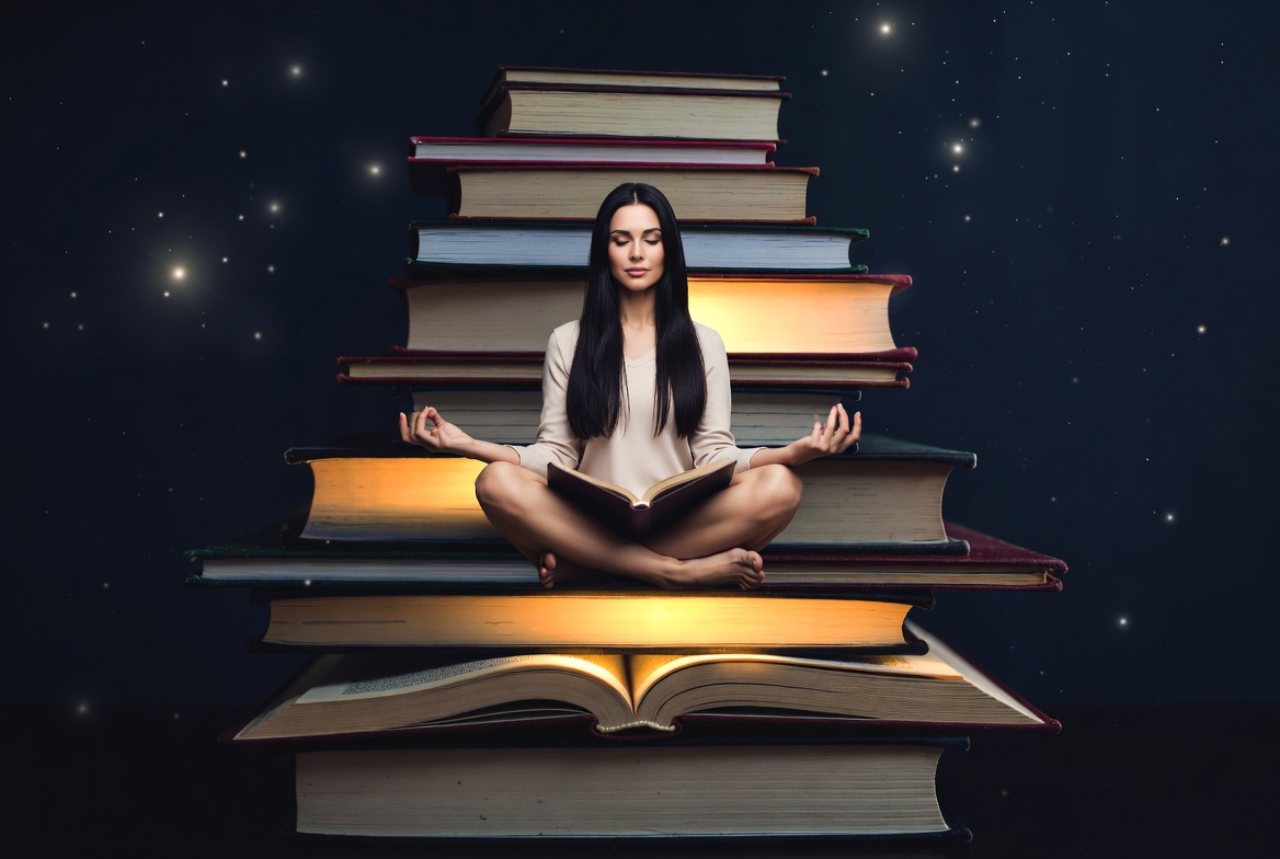 Woman meditating on stacked books Woman meditating on stacked books