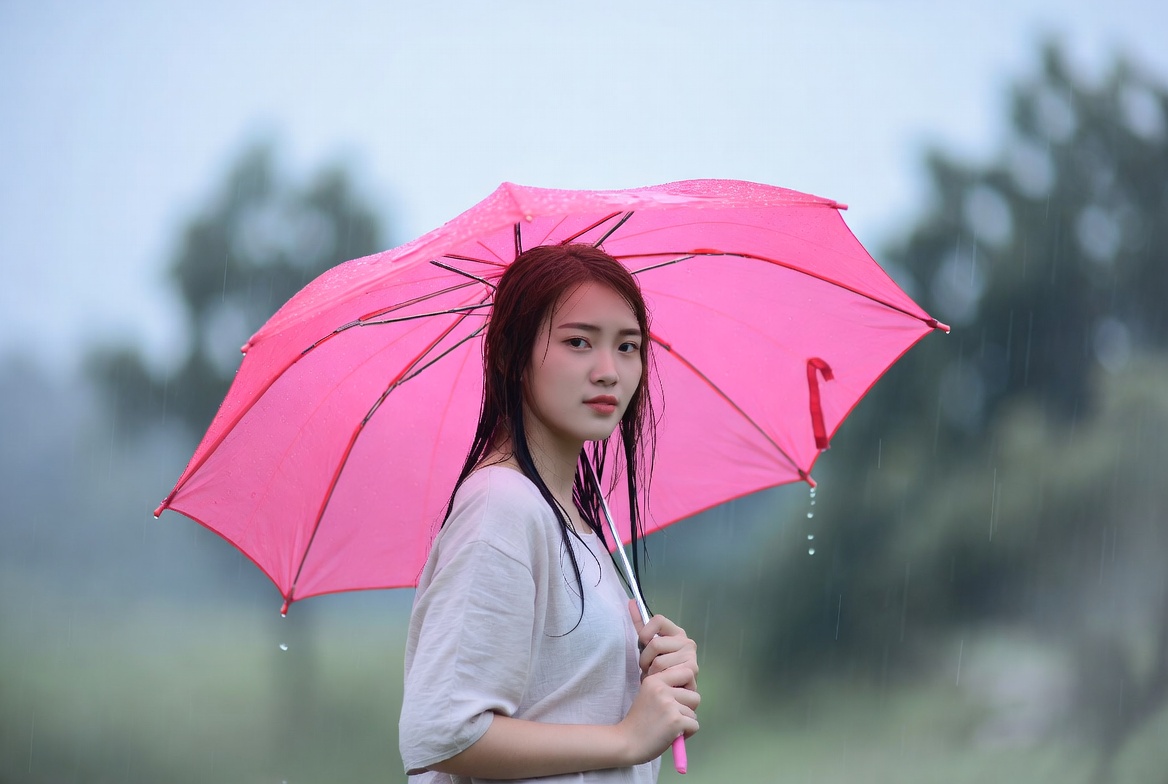Woman holding pink umbrella in rain Woman holding pink umbrella in rain