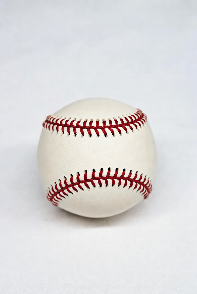White baseball with red stitching on surface White baseball with red stitching on surface