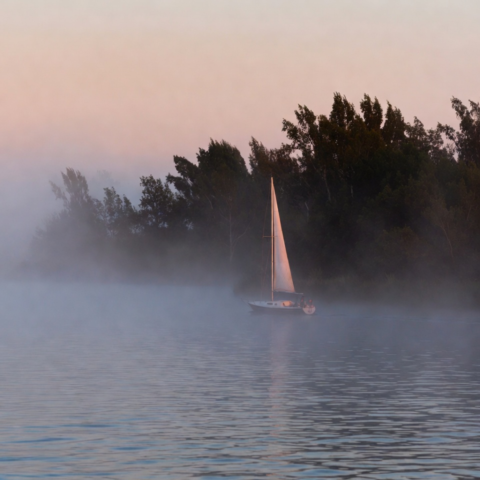 Sailboat on misty water at dawn Sailboat on misty water at dawn