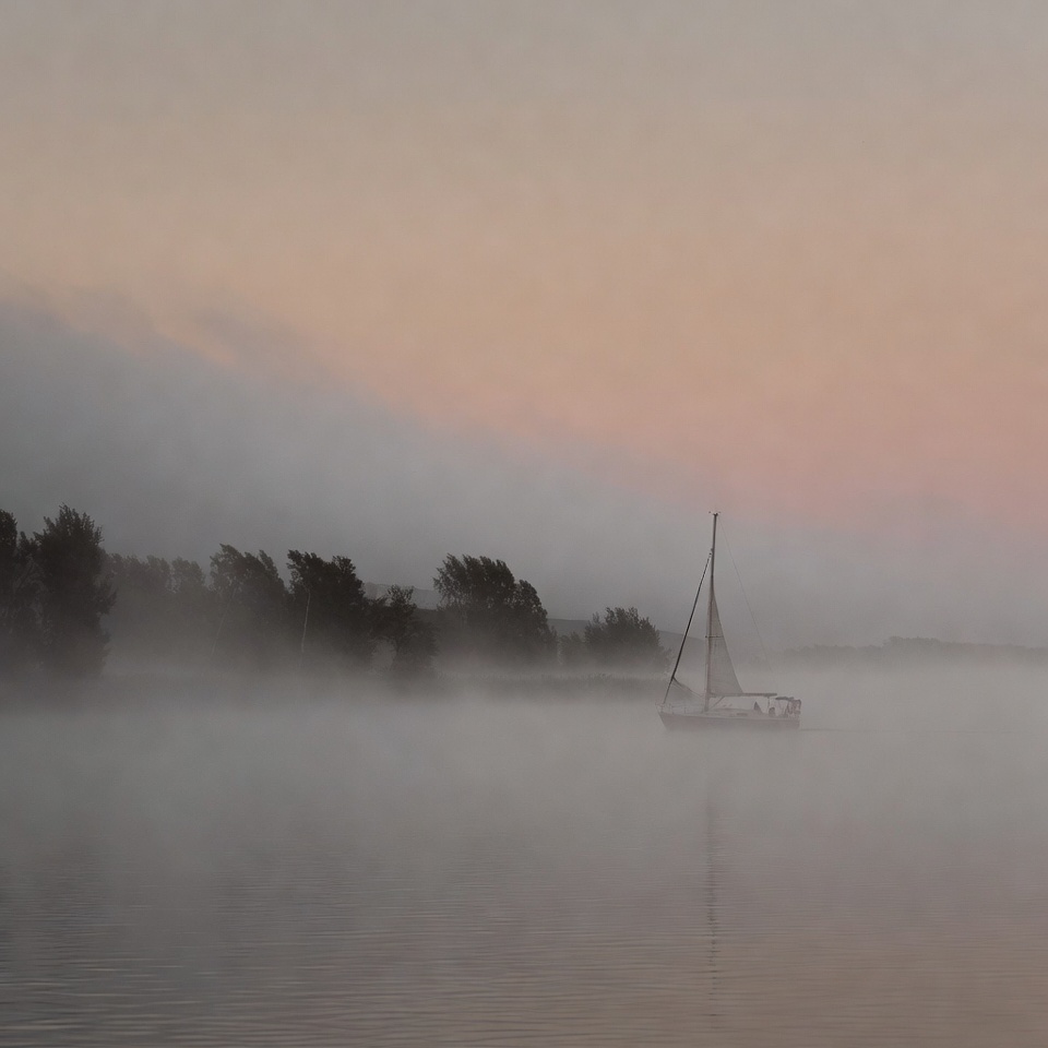 Sailboat on a foggy river at dawn Sailboat on a foggy river at dawn