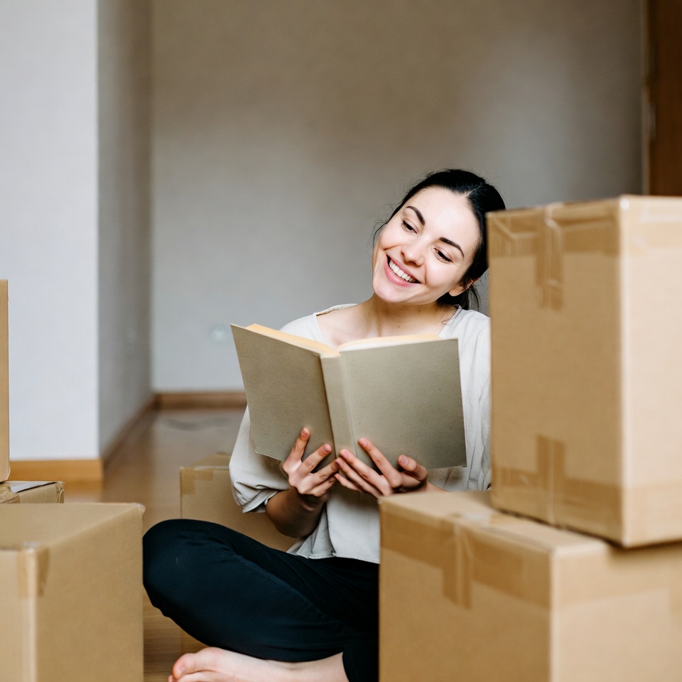 Woman reading book among boxes Woman reading book among boxes