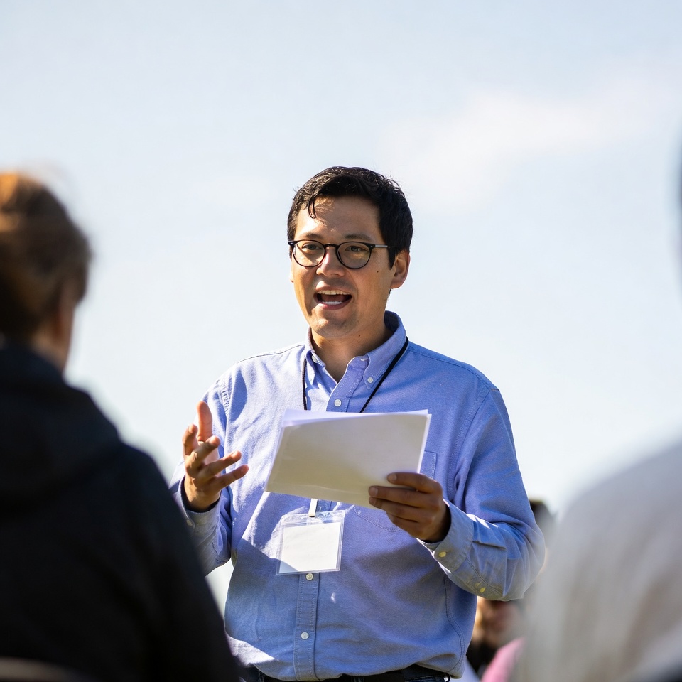 Man speaking to group outdoors in bright weather Man speaking to group outdoors in bright weather