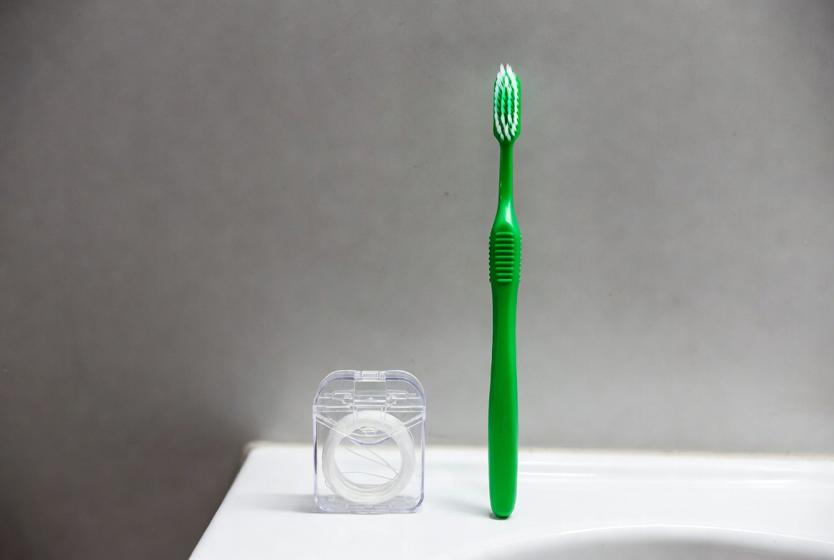Green toothbrush and floss on countertop Green toothbrush and floss on countertop