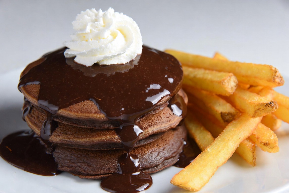 Chocolate pancakes with fries served together Chocolate pancakes with fries served together