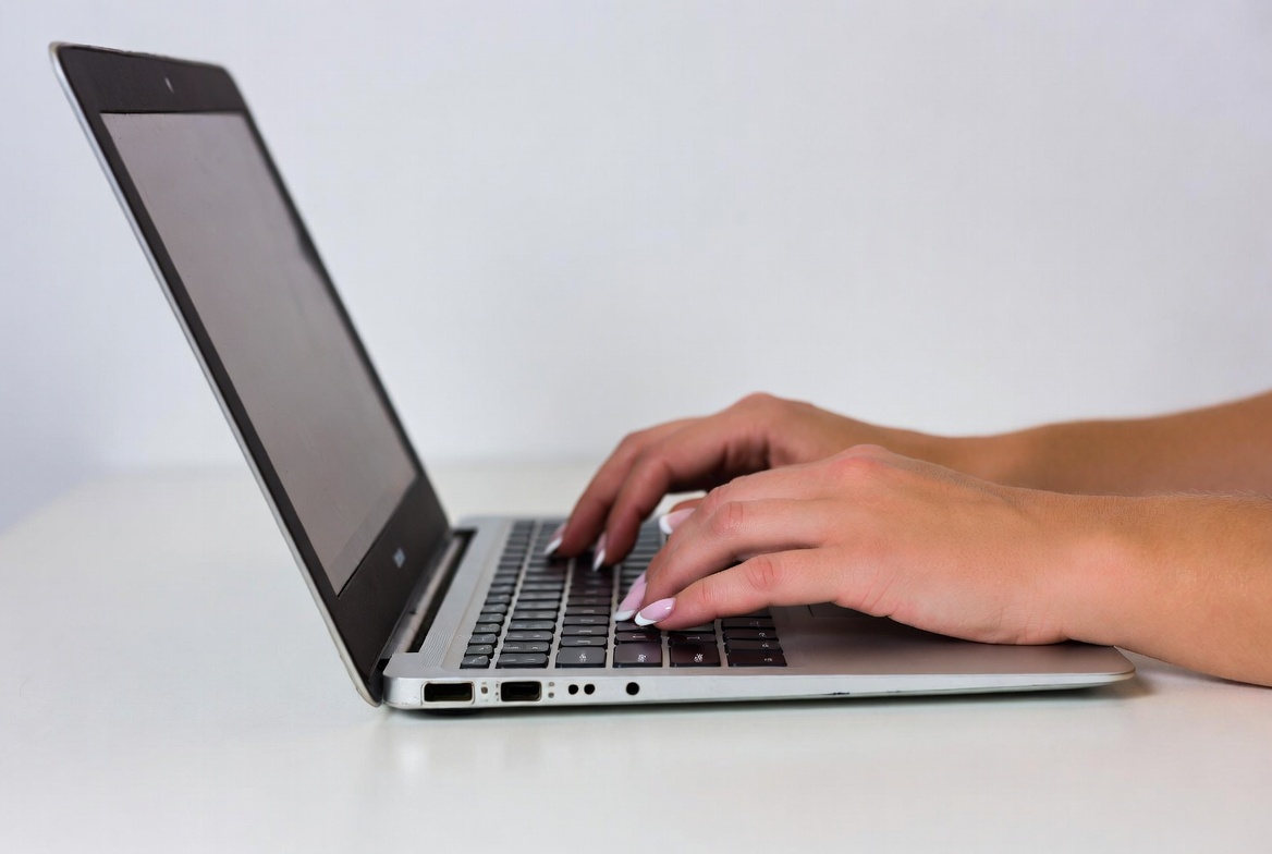 Typing on a laptop in a workspace Typing on a laptop in a workspace
