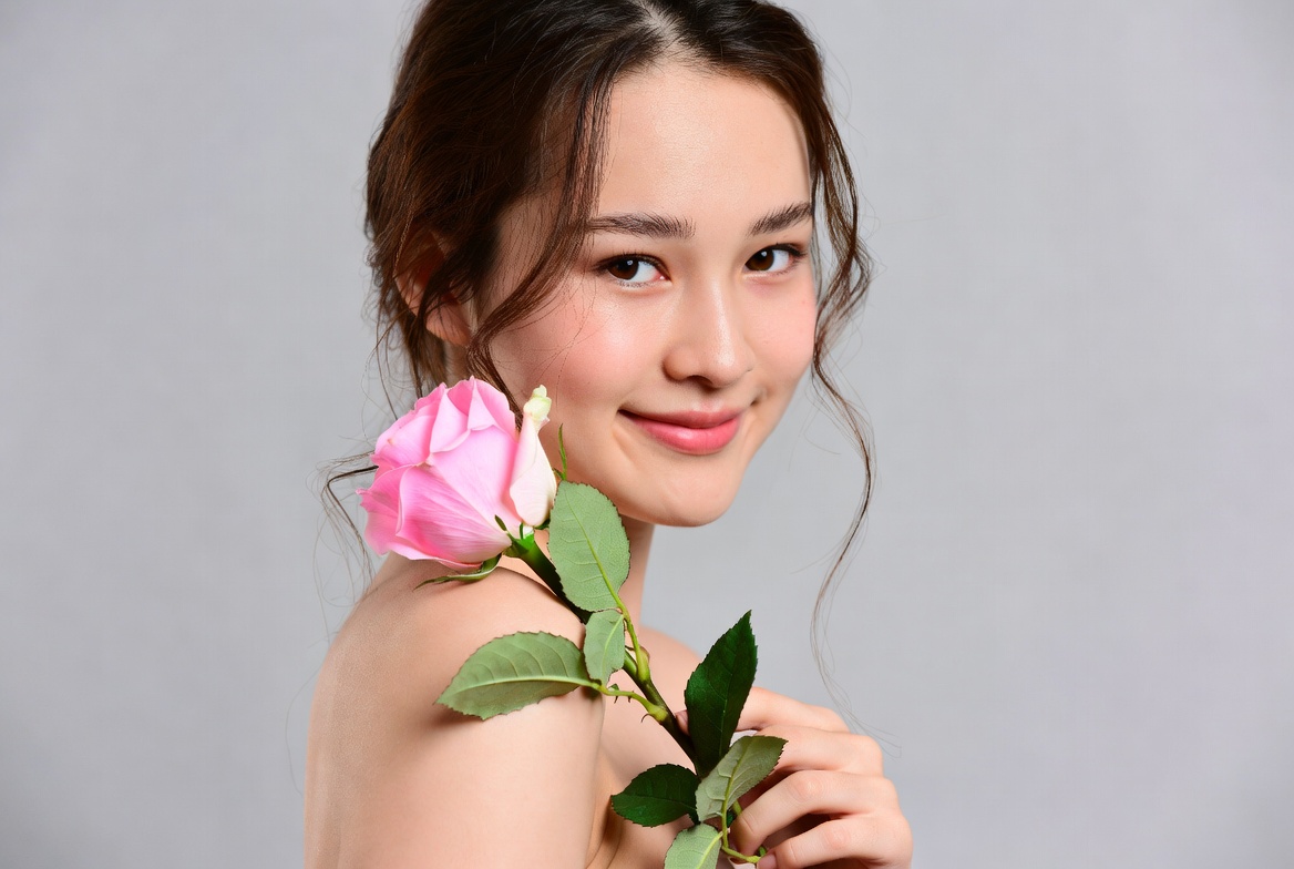 Woman holding rose flower indoors Woman holding rose flower indoors