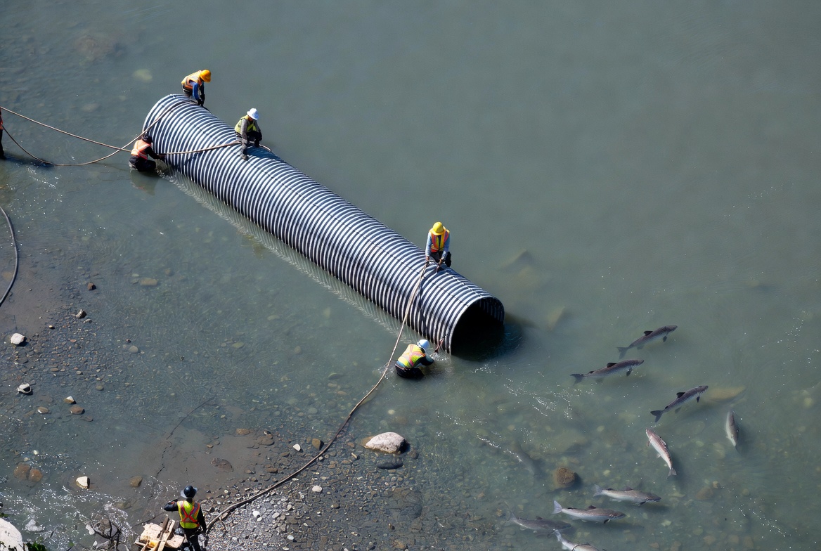 Workers repair pipe near water Workers repair pipe near water