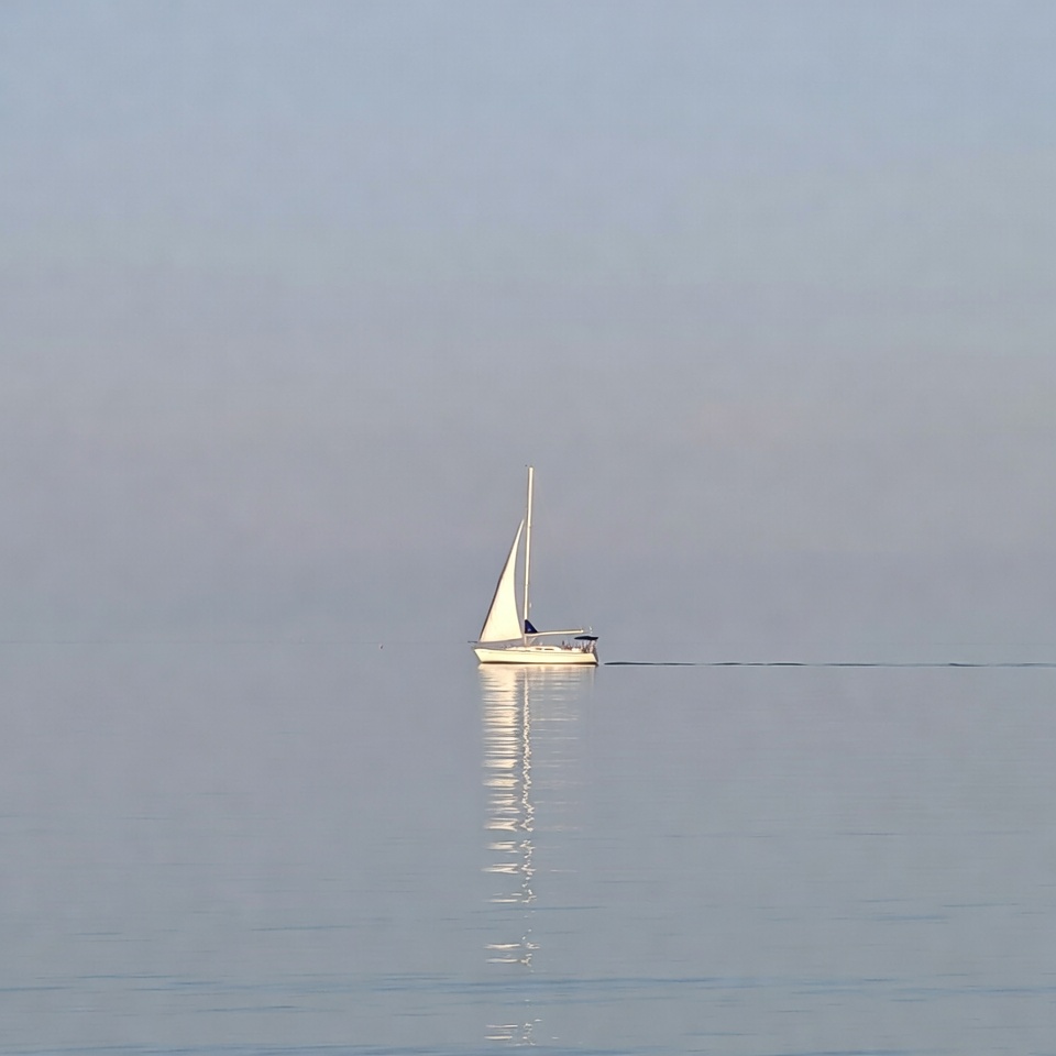 Sailboat on calm water at dawn Sailboat on calm water at dawn