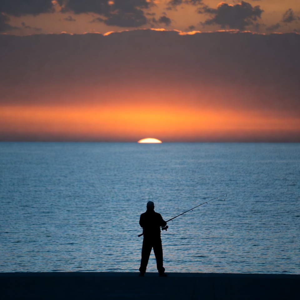 Fisherman at sunset by the sea Fisherman at sunset by the sea