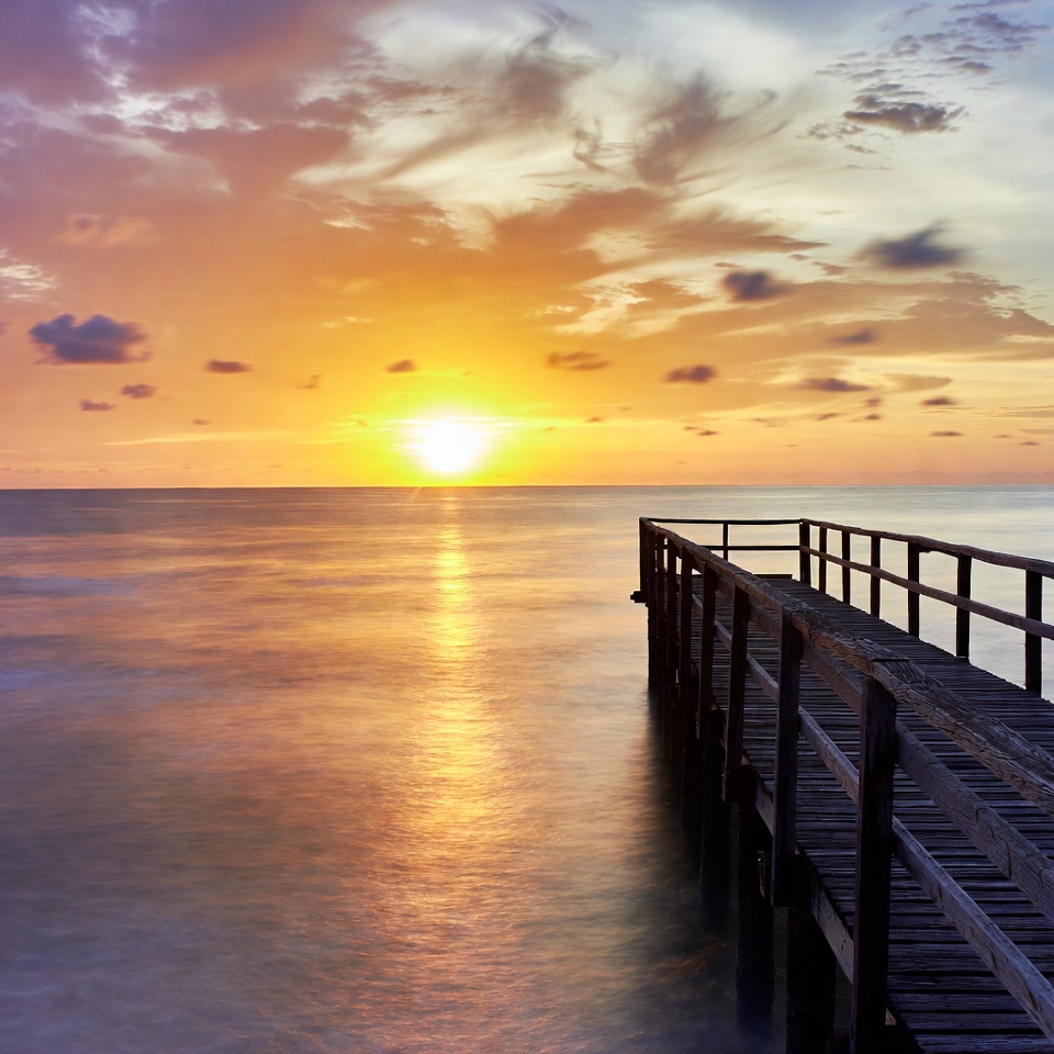 Sunset over wooden pier by water Sunset over wooden pier by water