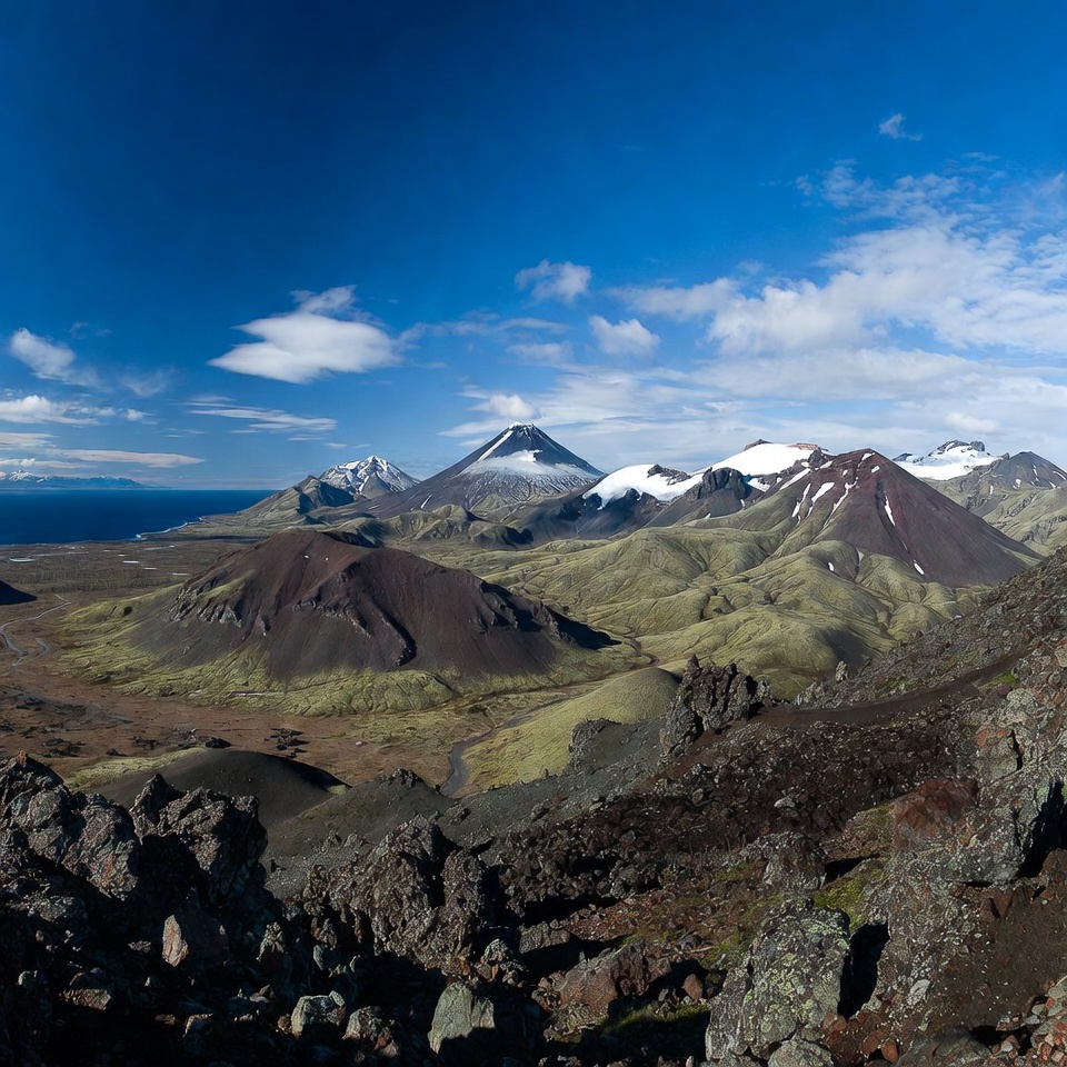 Snow-capped volcanoes in green valley Snow-capped volcanoes in green valley