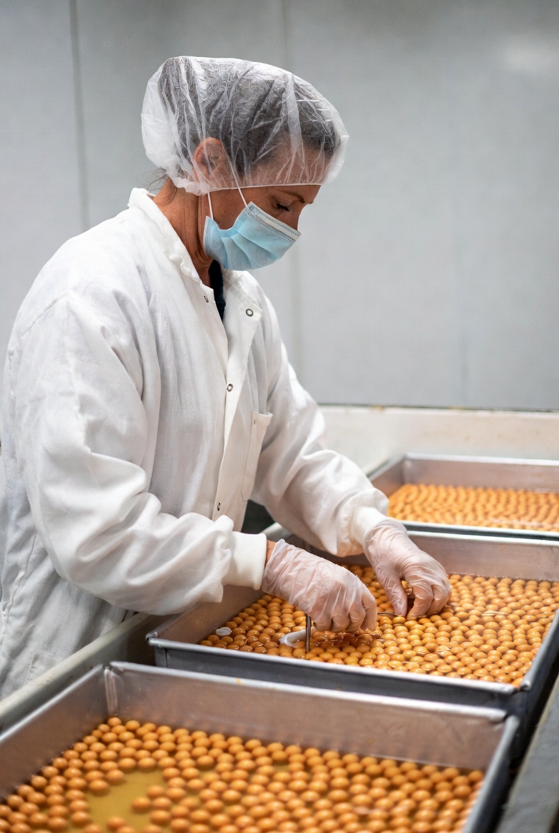 Woman handling orange beads in lab coat Woman handling orange beads in lab coat