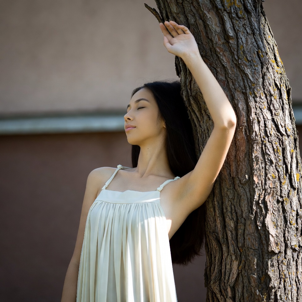 Asian woman leaning against tree Asian woman leaning against tree