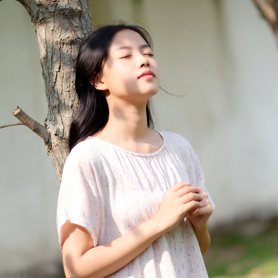 Asian woman praying by tree Asian woman praying by tree
