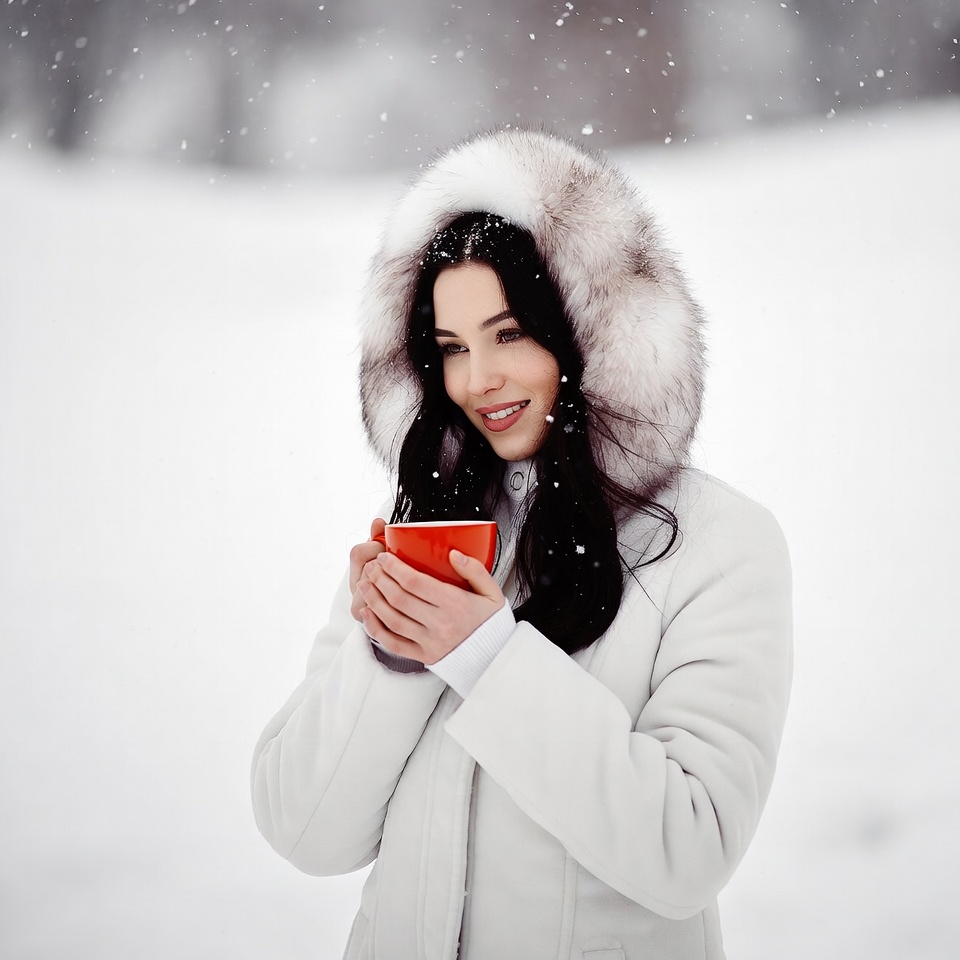 Woman sipping red mug in snowy winter Woman sipping red mug in snowy winter