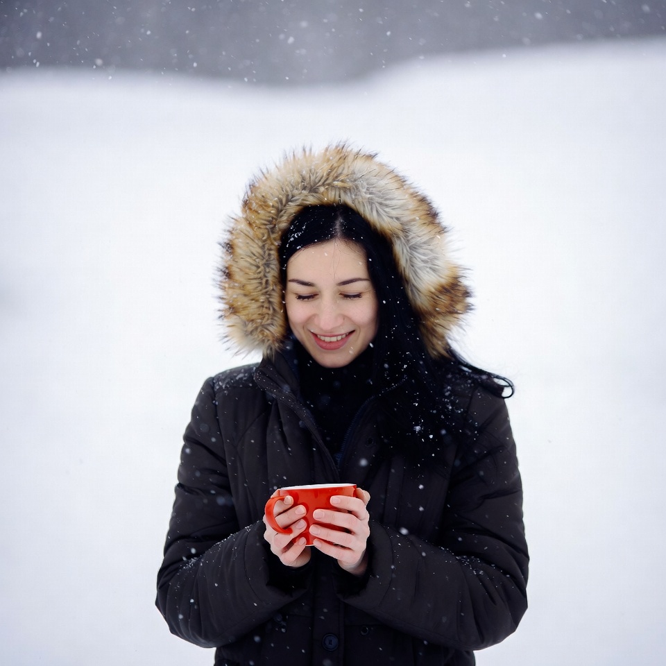 Woman sipping red mug in snow Woman sipping red mug in snow