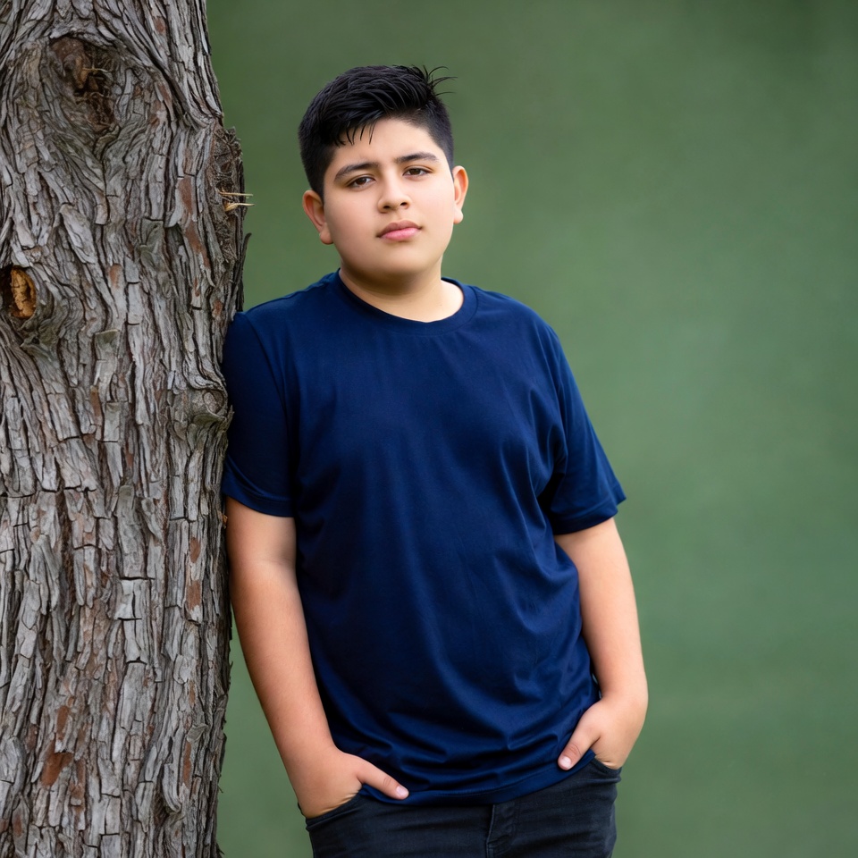 Latino boy leaning against tree Latino boy leaning against tree