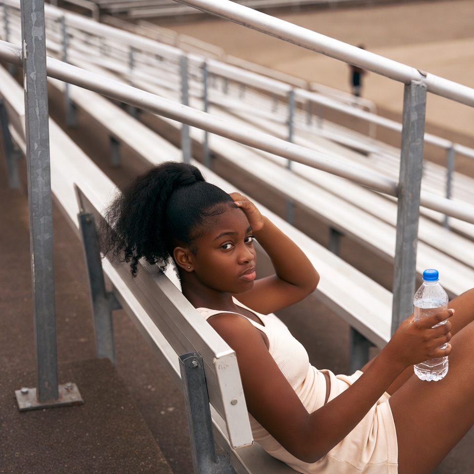African-American girl holding water bottle on bleachers African-American girl holding water bottle on bleachers