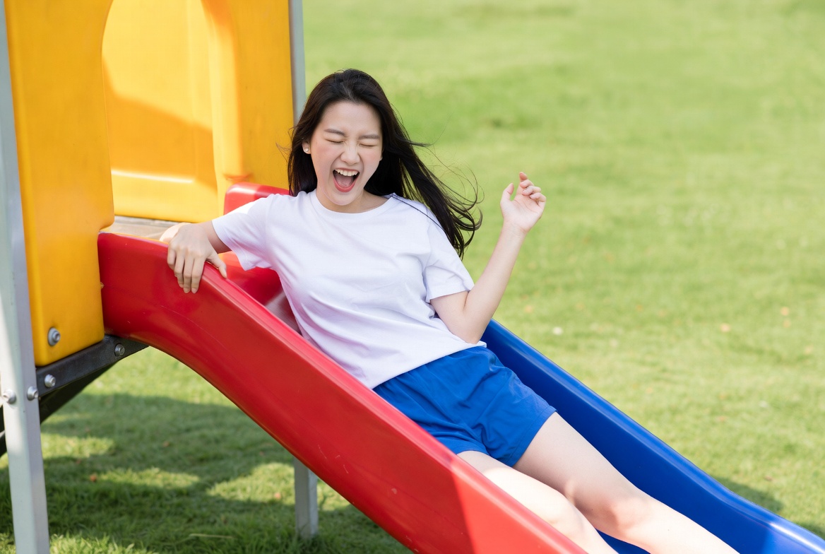 Asian girl sliding down playground slide Asian girl sliding down playground slide