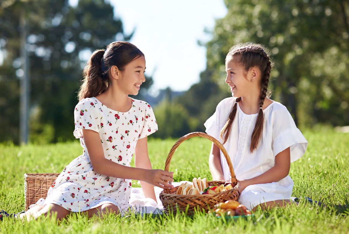 Two girls sharing picnic basket outdoors Two girls sharing picnic basket outdoors