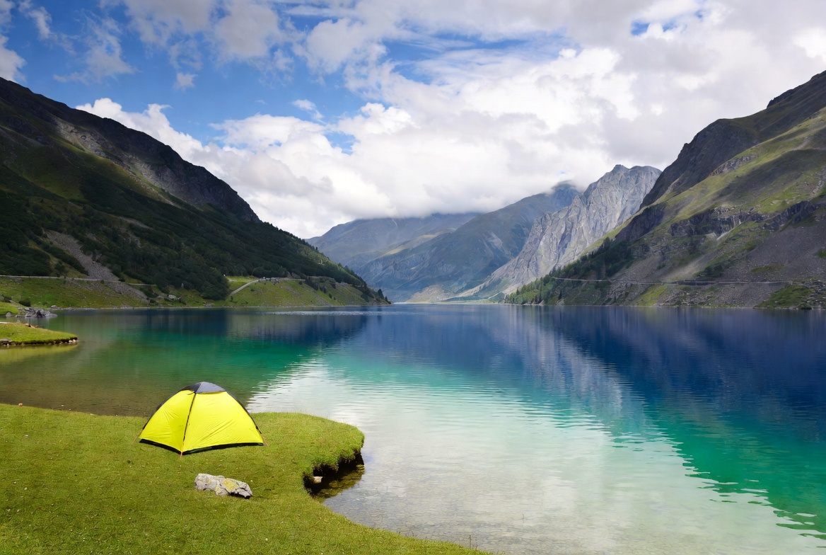 Yellow tent by alpine lake mountains Yellow tent by alpine lake mountains