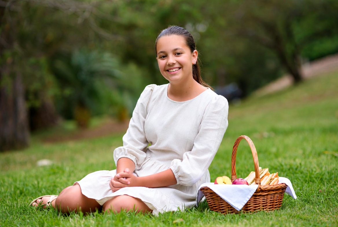 Girl sitting with picnic basket on grass Girl sitting with picnic basket on grass