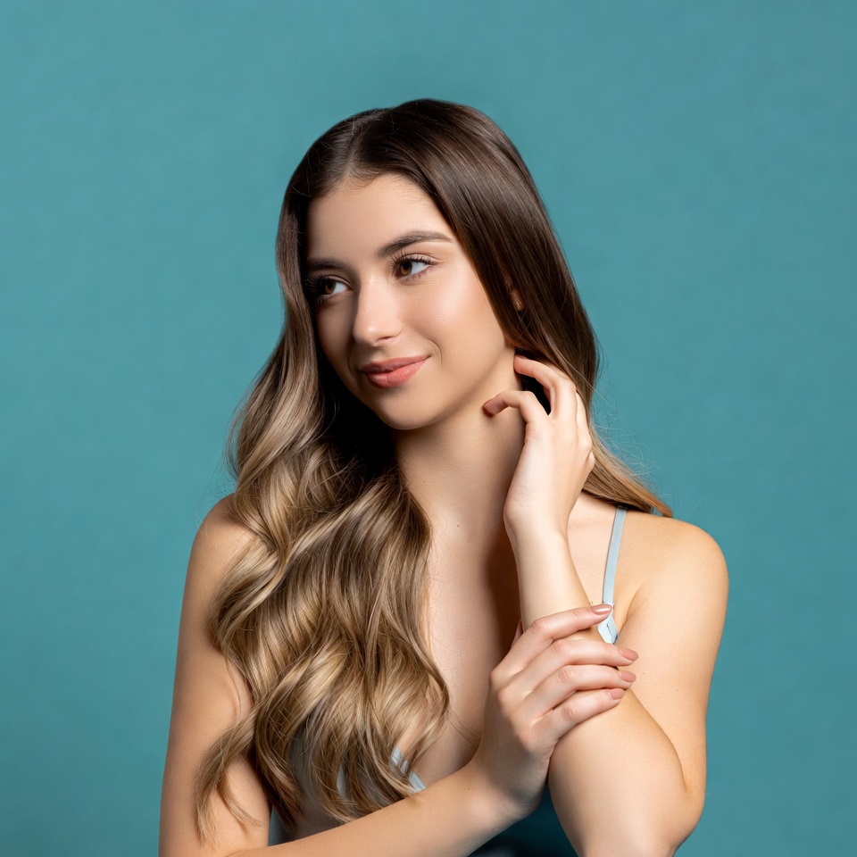 Young woman with wavy hair on blue background Young woman with wavy hair on blue background