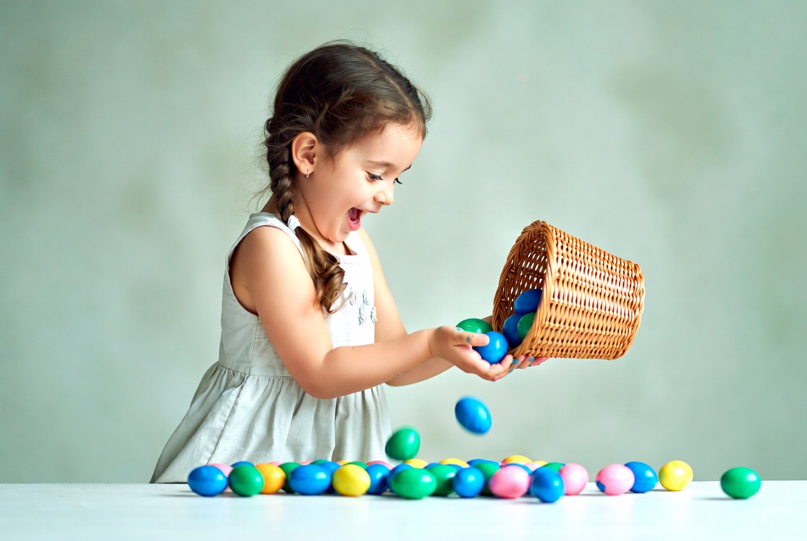 Girl pouring colorful Easter eggs from basket Girl pouring colorful Easter eggs from basket