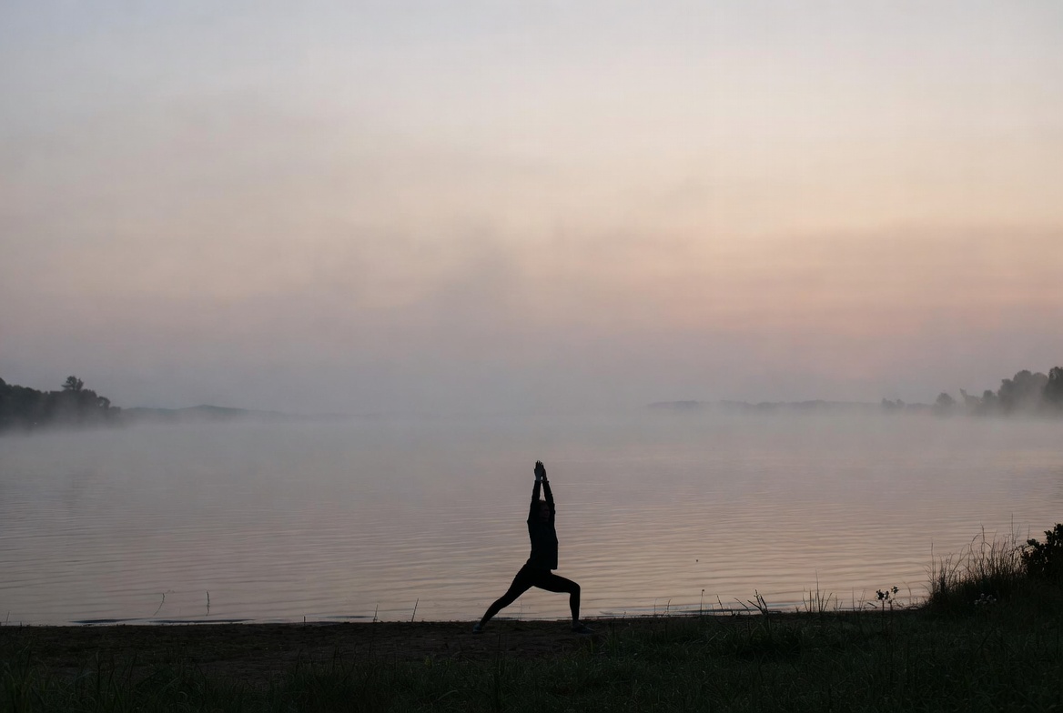 Silhouette woman practicing yoga by lake Silhouette woman practicing yoga by lake