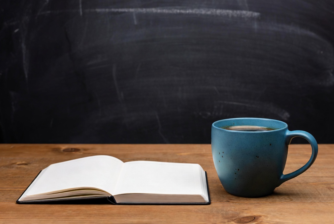 Open notebook and blue mug on table Open notebook and blue mug on table