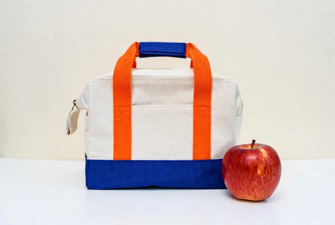 White lunch bag with orange handles and red apple White lunch bag with orange handles and red apple